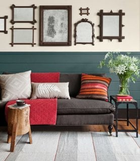 Canapea fixa de doua locuri si perne decorative colorate si colectie de rame pe perete
