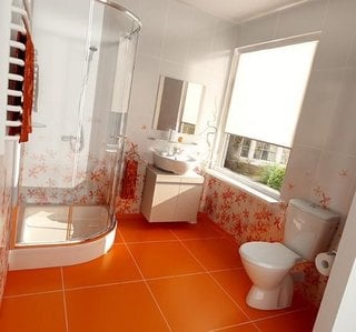 Baie cu faianta alba cu flori portocalii si gresie portocalie simpla cu cabina de dus pe colt