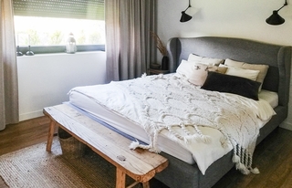 Dormitor cu pat dublu gri si parchet din lemn