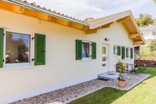 Casa micuta cu parter cu fatada alba si obloane din lemn de culoare verde