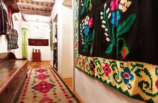 Casa traditionala cu covoare romanesti pe podea si pereti