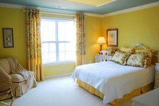 Dormitor zugravit cu galben pal si draperii cu model floral