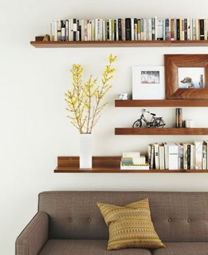 Etajere inegale din lemn asezate deasupra canapelei gri din living