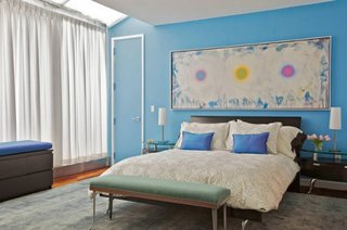Dormitor confortabil amenajat cu bleu si alb si o frumoasa pictura abstracta in culori asortate