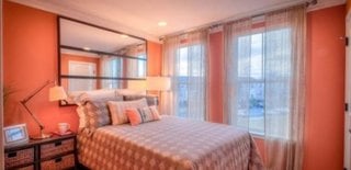 Dormitor amenajat in culoarea piersicii si oglinda mare deasupra patului