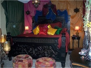 Dormitor cu materiale colorate pe perete si multe perne de decor