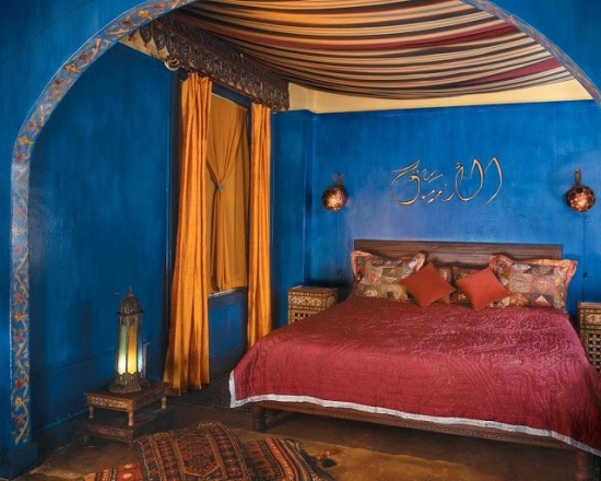 Dormitor marocan cu peretii albastru safir si accesorii rosii rubiniu