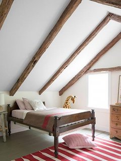 Dormitor simplu amenajat la mansarda cu covor tesut rosu cu alb
