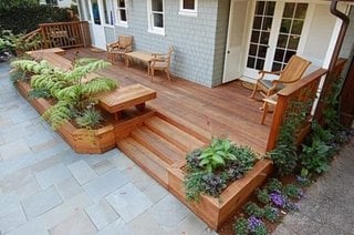 Terasa in fata casei din lemn cu bancuta si jardiniere cu flori