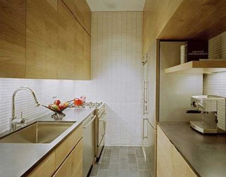 Bucatarie dintr-un mic apartament cu dulapuri din lemn natur