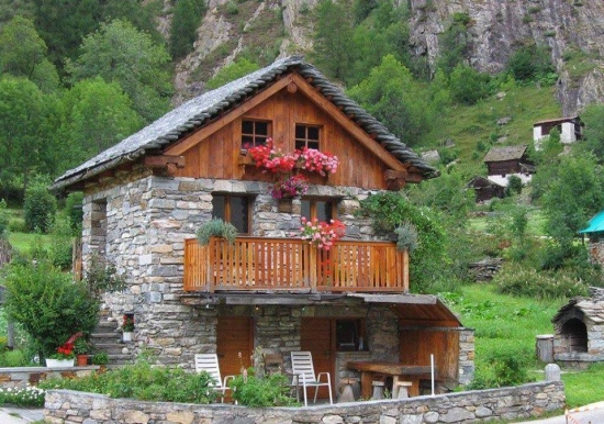 Casa rustica din piatra si lemn cu muscate la balcon