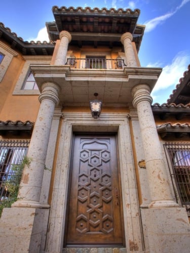 Usa de exterior cioplita in lemn masiv la o casa in stil toscan cu coloane de piatra