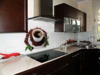 Mobilier de bucatarie maro inchis si perete alb cu imagine cana cu cafea